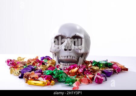 Composizione del cranio ridente di Halloween con trucco o caramelle trattamento su sfondo bianco Foto Stock