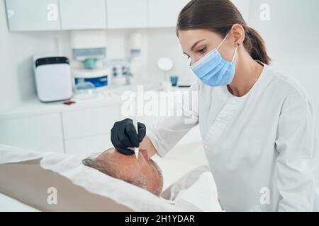 Cosmetologo che esegue la pulizia della cura della pelle in clinica Foto Stock