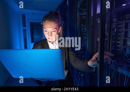 Tecnico di sistema che utilizza il laptop per analizzare il server Foto Stock
