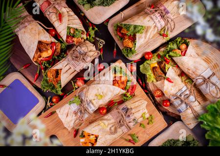 varietà diversa di rotoli di pollo o avvolgere su piatto di legno e sfondo nero.copia vista paesaggistica.top. Foto Stock