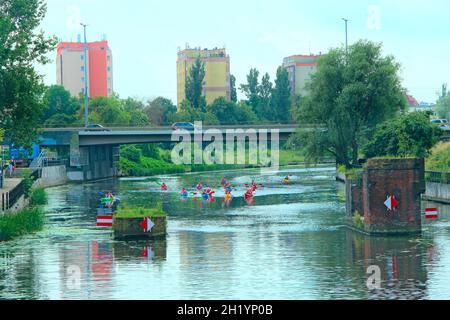 gruppo di persone navigano in kayak lungo il fiume sotto il ponte. Vacanze estive dopo la quarantena. Kayak sul fiume. Amici che trascorrono del tempo insieme Foto Stock