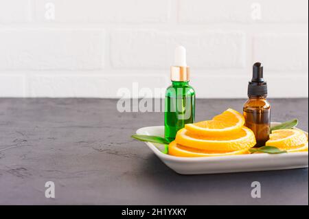 flaconi cosmetici con siero arancione per la cura quotidiana della pelle. una fase aggiuntiva di idratazione Foto Stock