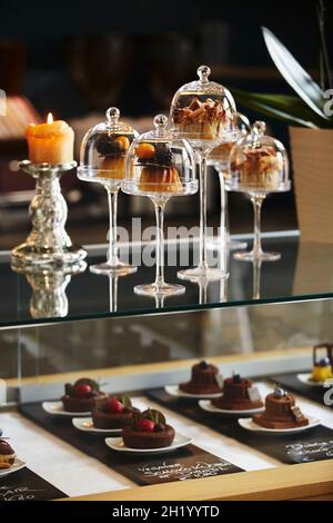 Dolci sotto mini chiodi di vetro su un bar in un ristorante Foto Stock