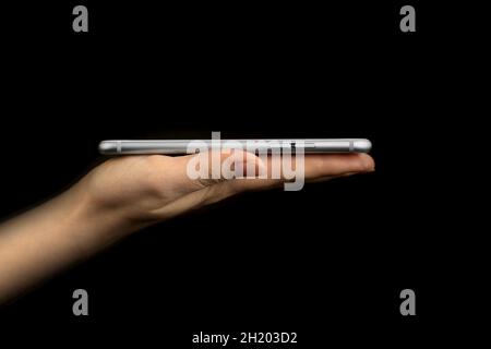 Vista laterale del telefono cellulare con supporto a mano per presenazione, scatto in studio, modello o mockup su sfondo nero Foto Stock