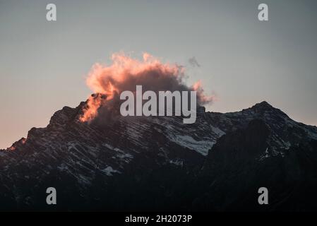 Nuvola appesa su una cima di montagna al tramonto. Perfetto per la carta da parati e lo sfondo per volantini o homepage. Foto Stock