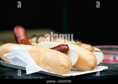 Un hot dog e uno spiedino di pollo alla griglia su un piatto di carta Foto Stock