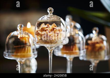Dolci sotto mini chiodi di vetro su un bar in un ristorante Foto Stock