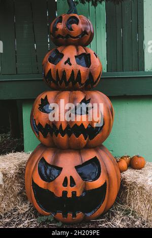 Tre zucche decorative di Halloween Jack-o-Lantern, una in cima all'altra, sulla strada. Halloween e festa di carnevale concetto. Foto Stock