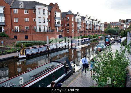 Le barche strette del canale ormeggiate sulla linea vecchia del canale di Birmingham con gli edifici di appartamenti moderni (corte sinfonica, Regno Unito Foto Stock