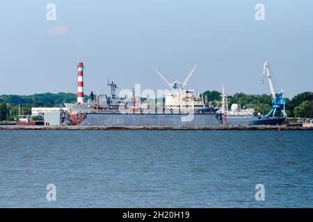 Cantiere navale per la riparazione e la manutenzione di navi, revisione di navi da carico nel bacino di riparazione. Cantiere sul lavoro. Macchine e gru industriali. Trasporto, fre Foto Stock