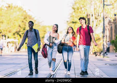 Gruppo di amici di diverse etnie a piedi in una strada pedonale Foto Stock