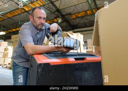 addetto al magazzino che esegue la scansione di una spedizione Foto Stock