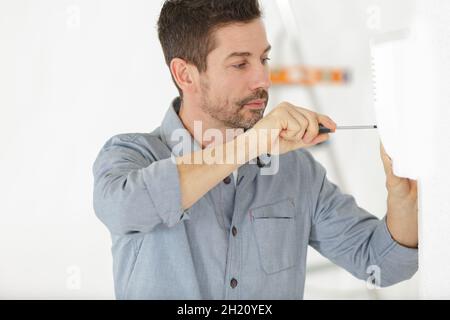 un uomo sta avvitando un muro Foto Stock