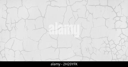 Foto di qualità della vecchia parete dipinta di bianco con crepe. Sfondo con un bel disegno astratto su una parete invecchiata. Foto Stock
