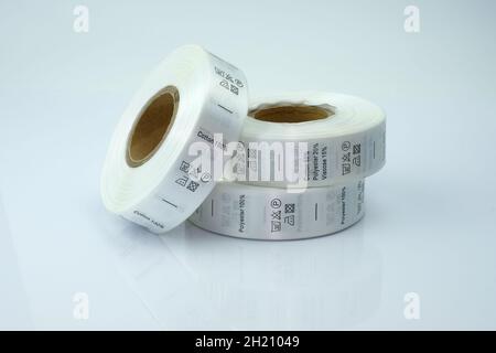 Cartellini a matassa per abbigliamento, nastro satinato con simboli per l'uso di abbigliamento. Matasse bianche, un rotolo di nastro con informazioni sul lavaggio e sulla composizione del tessuto Foto Stock