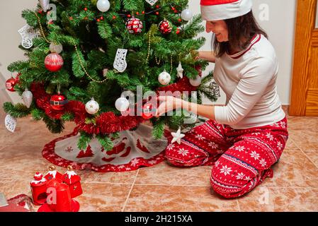 Donna che decora albero di natale nel suo soggiorno Foto Stock