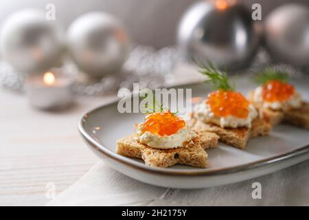 Canapes vacanza con caviale rosso, panna e aneto guarnire su pane tostato a forma di stella su un piatto grigio, decorazione natalizia in argento festivo, copia spac Foto Stock