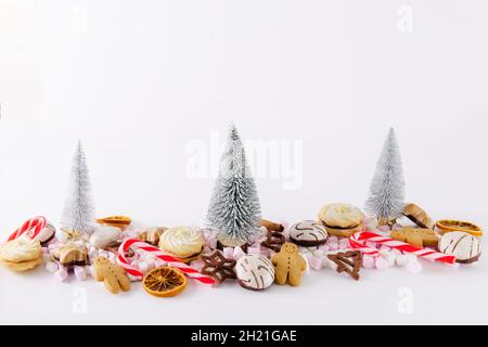 Dolci e biscotti di Natale con decorazioni natalizie su sfondo bianco. Foto Stock