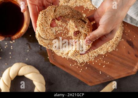 Delizioso bagel turco con semi di sesamo noti come susamli simit. L'immagine dall'alto mostra come modellare l'impasto intrecciato e assicurarsi che il sesamo si attacca al surf Foto Stock