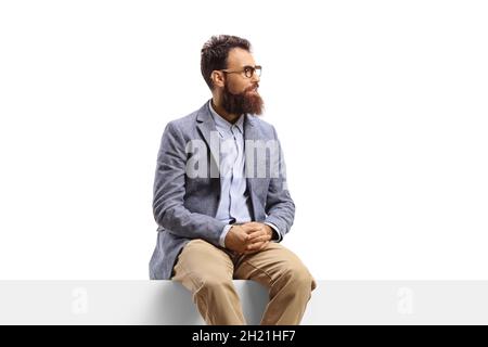 Uomo bearded seduto su una bandiera che guarda al lato isolato su sfondo bianco Foto Stock