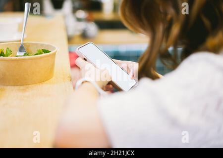 Primo piano Donna in un caffè lettura, SMS, guardare video, scorrimento social network, fare note, acquisti online sul suo cellulare. Donna Bisness Foto Stock