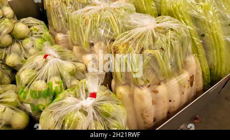 Le verdure sono in sacchetti di plastica negli scaffali per la vendita. Foto Stock