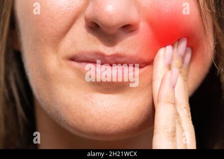 Donna sensazione di dolore ai denti con area evidenziata in rosso. Donna che soffre di mal di denti o malattie dentistiche Foto Stock