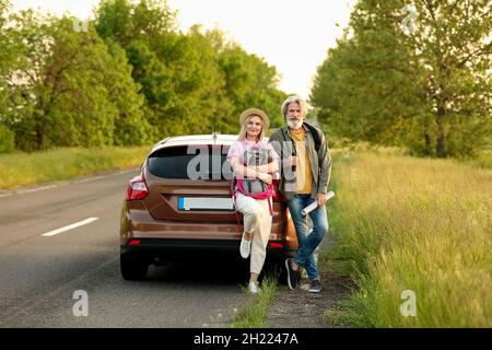 Coppia matura felice con zaini e mappa vicino auto in campagna Foto Stock