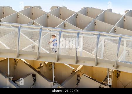 Piccolo ragazzo che corre sulle passerelle di Setas de Sevilla, costruzione in legno con passerelle sul tetto a Siviglia, Andalusia, Spagna Foto Stock