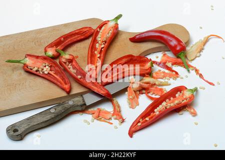 Peperoni rossi tagliati su tavola di legno con coltello, Germania Foto Stock