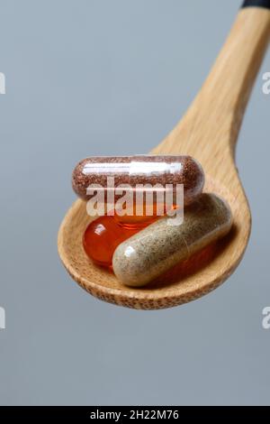 Capsule con integratore alimentare e acido grasso omega-3 in cucchiaio di legno Foto Stock