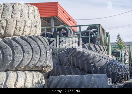 Vecchi pneumatici impilati insieme in un garage di officina Foto Stock