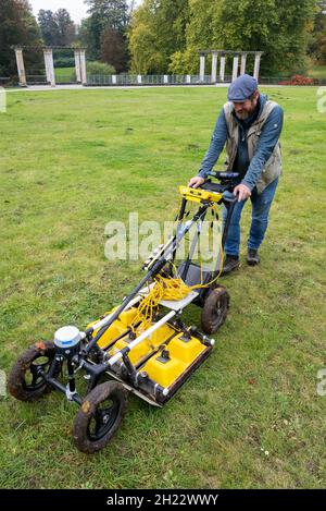 Putbus, Germania. 19 Ott 2021. Immo Trinks dell'Università di Vienna lavora nel parco del castello con un cosiddetto radar a penetrazione di terra. Il dispositivo è stato utilizzato per esplorare il sito dove un tempo sorgeva il castello. Insieme alle fotografie, sul computer deve essere creato un modello di strutture sopra e sotto terra. L'azione fa parte del centro maniero dell'Università di Greifswald, dal quale si ricercano fino a 15,000 manieri e castelli della regione baltica. (A dpa 'High-tech rasaerba esamina resti di Putbus Castello') credito: Stefan Saae/dpa/Alamy Live News Foto Stock