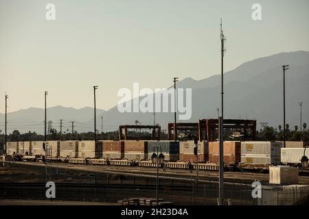 San Bernardino, California, USA - 10 ottobre 2021: Un treno cargo stack nel tardo pomeriggio arriva in una struttura intermodale da scaricare. Foto Stock