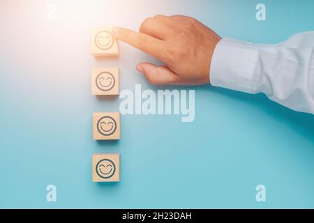 La migliore eccellente valutazione dei servizi di affari con il viso felice e sorrise al concetto di esperienza del cliente di cinque segno di spunta corretto sul blocco di legno su blu Foto Stock