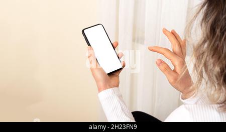 Donna che tiene smartphone con schermo mockup. Foto Stock