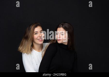 Ritratto di due donne felici amici con gesti amorevoli ridendo su sfondo nero - concetto di amicizia Foto Stock