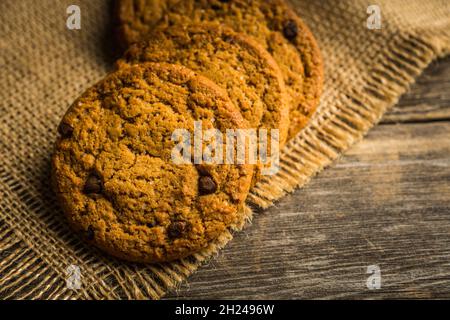 Biscotti freschi e sani con cioccolato e semi sullo sfondo rustico. Messa a fuoco selettiva. Profondità di campo poco profonda. Foto Stock