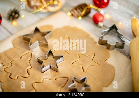 Vista dall'alto dell'impasto crudo per biscotti, tagliatubi e decorazioni natalizie su tavola di legno. Concetto di cibo dolce di Natale Foto Stock