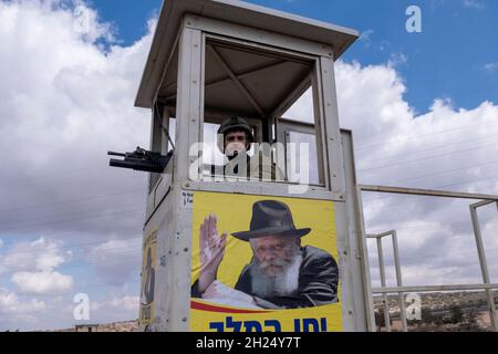 Un soldato israeliano si erge in una torre di guardia militare con l'immagine del Rabbino Menachem Mendel Schneerson considerato uno dei più influenti leader ebrei del XX secolo a Zatara o Tapuah giunzione vicino alla città palestinese di Nablus il 19 ottobre 2021 in Cisgiordania, Israele. Attualmente, la maggior parte della Cisgiordania è amministrata da Israele anche se il 42% di essa è sotto vari gradi di autonomia da parte dell'autorità palestinese gestita da Fatah. Foto Stock