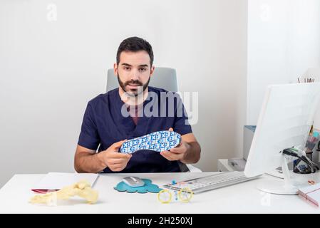 Medico seduto alla sua scrivania mostrando un sottopiede Foto Stock