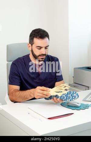 Medico nel suo ufficio che mostra uno scheletro del piede e una soletta per spiegare come l'impronta dovrebbe essere eseguita. Foto Stock