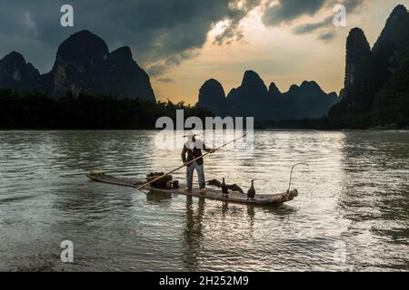 Un tradizionale pescatore cormorano su una zattera di bambù con i suoi cormorani sul fiume li, Xingping, Cina. Foto Stock