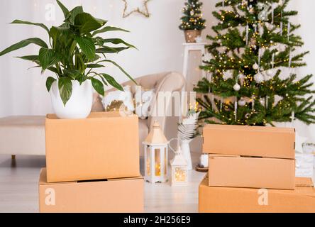 In Movimento per la casa nuova per il concetto di Natale. Focus sulla delocalizzazione di cartone scatole e albero di Natale decorato con presenta sotto di esso sullo sfondo Foto Stock