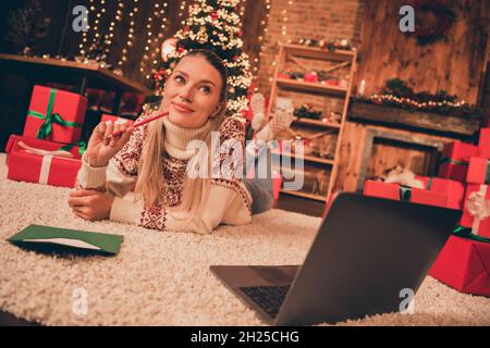 Foto di adorabile signora giovane sognante vestito stampa pullover scrittura natale congratulazioni sorridente casa camera interna Foto Stock