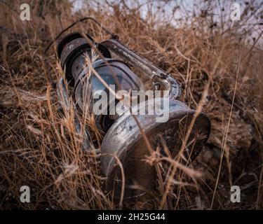 La lampada del cherosene o della paraffina è una vecchia lampada del gas nel mezzo delle erbacce della terra. Foto Stock
