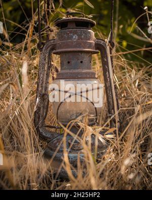 La lampada del cherosene o della paraffina è una vecchia lampada del gas nel mezzo delle erbacce della terra. Foto Stock