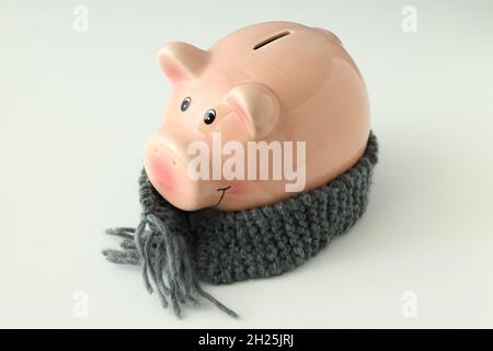 Pig bank con sciarpa in maglia su sfondo bianco. Foto Stock