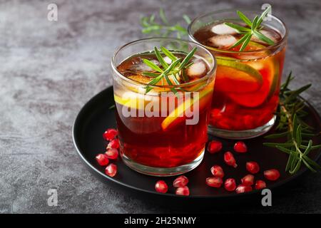 Cocktail di melograno decorato con lime, rosmarino e ghiaccio, bevanda fredda Foto Stock