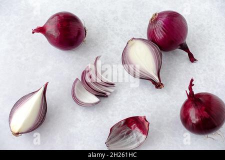 Composizione di cipolle rosse intere, tagliate a metà e tagliate in quattro con spazio per la copia. Vista ravvicinata e ad angolo alto. Foto Stock